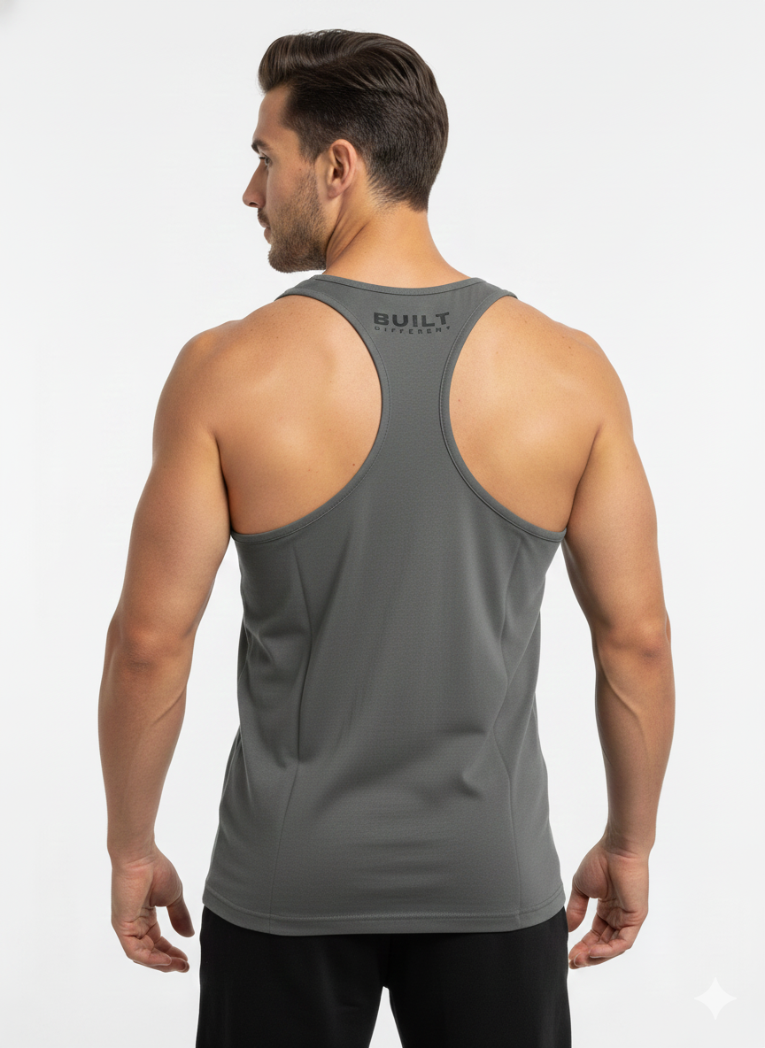 A man with dark hair, facing away, wears the Men's Gym Clothes AU BDHQ Racer Back Vest (180GSM) – Classic Cut, Lightweight Stretch in gray with "BUILT" on the upper back and black shorts, standing against a plain white background.